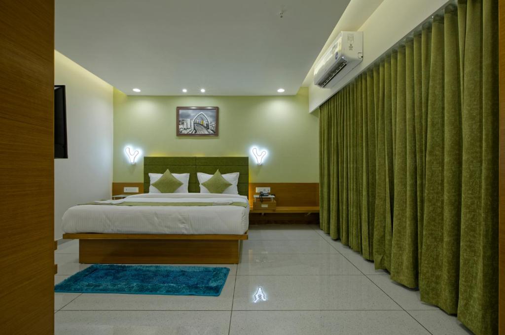 SarkhejHOTEL AURELLIA的一间卧室配有床和绿帘