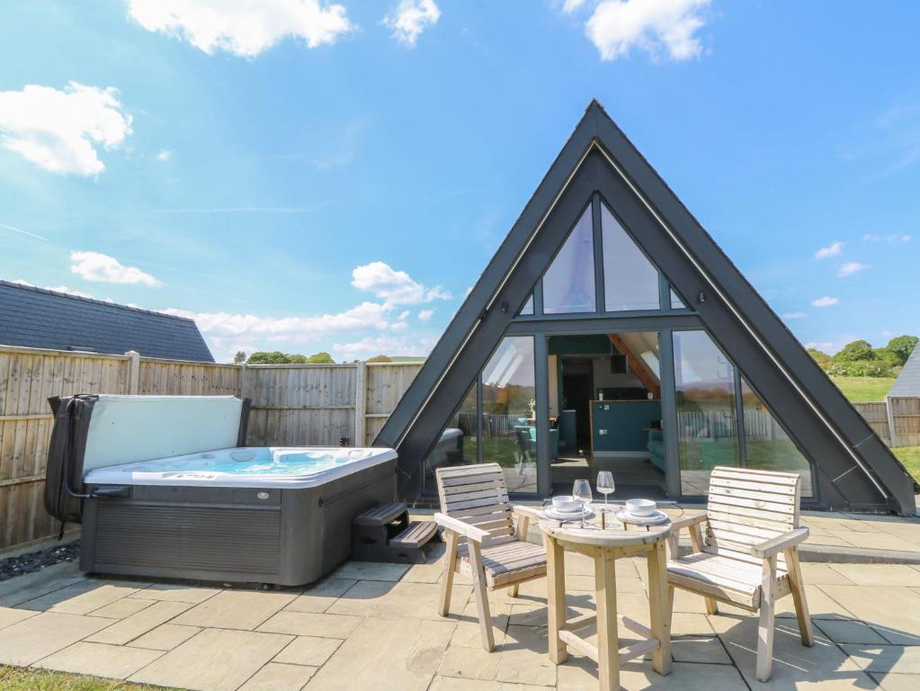 a patio with a hot tub and a table and chairs at Kerry Hill - The Sheepfold in Llandrindod Wells
