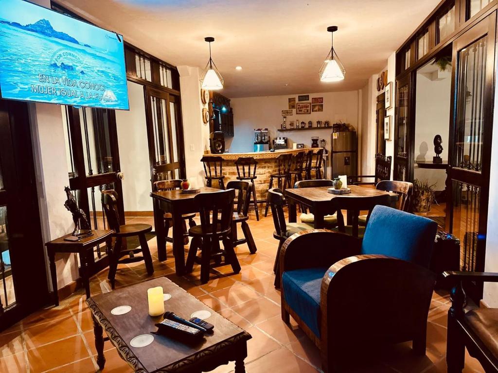 a living room with tables and chairs and a large screen at Acaima Café Lodge in Sasaima