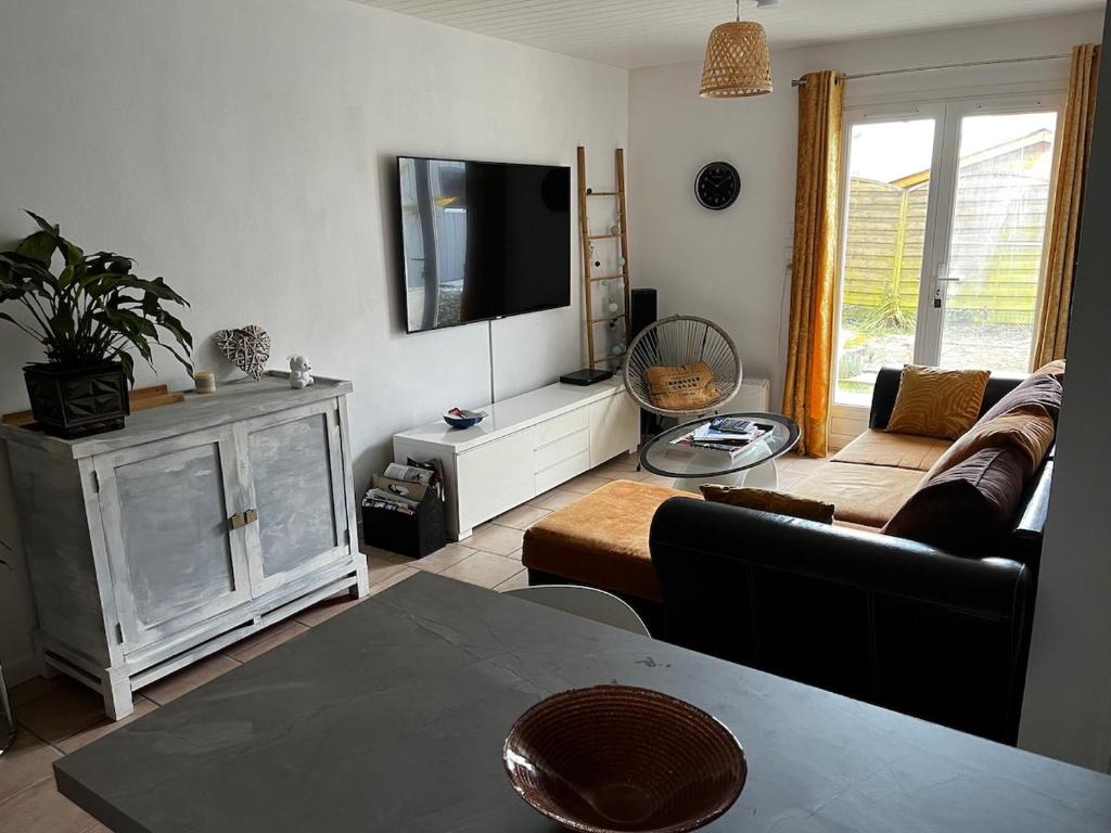 un salon avec un canapé et une télévision à écran plat dans l'établissement Villa Riva-Bella, à Ouistreham