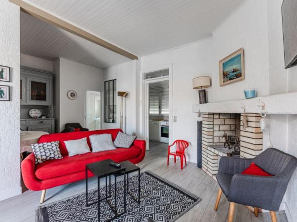 a living room with a red couch and a fireplace at Maison Landaise Charme Proche Océan, Animaux Acceptés - FR-1-521-254 in Biscarrosse