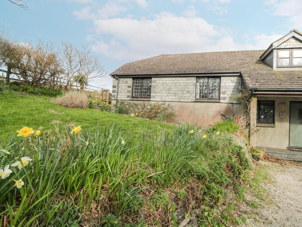 an old house with flowers in the yard at Wringford Farm Annexe in Torpoint