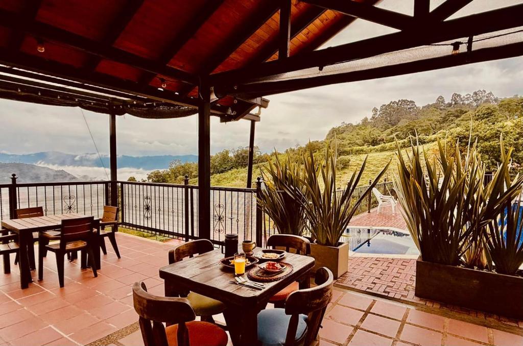a patio with tables and chairs and a view of the mountains at Acaima Café Lodge in Sasaima