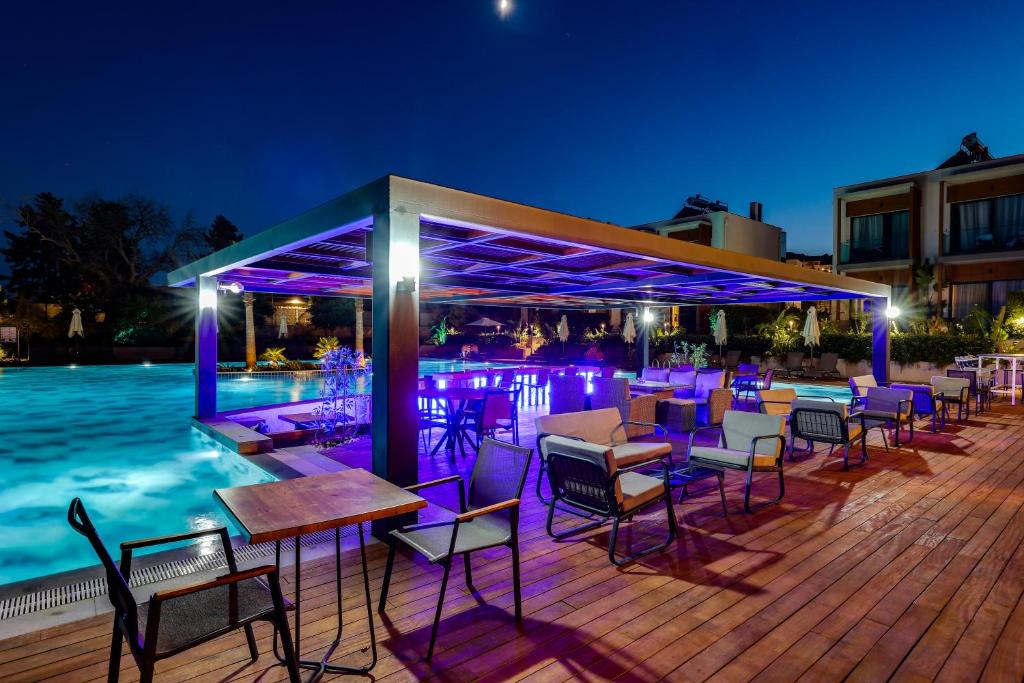 a bar with chairs and tables next to a pool at Celeste Bella Luxury Hotel & Spa in Ortakent