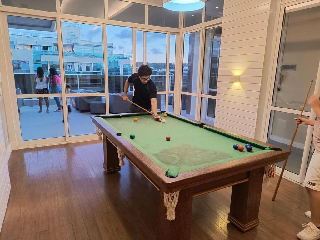 ブラジリアにあるAp alto padrão Noroeste Brasília com garagem coberta, wi-fi e área de lazer com piscina e academiaのビリヤード台付きの部屋で男性が遊ぶ