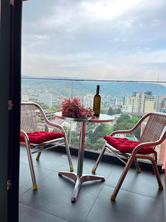 2 sillas y una mesa con una botella de vino en el balcón en Old City Apartment, en Tiflis