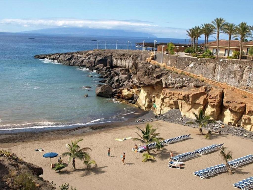 a beach with umbrellas and people on the sand at Apartamento vista al mar y Piscina en Playa Paraiso in Playa Paraiso