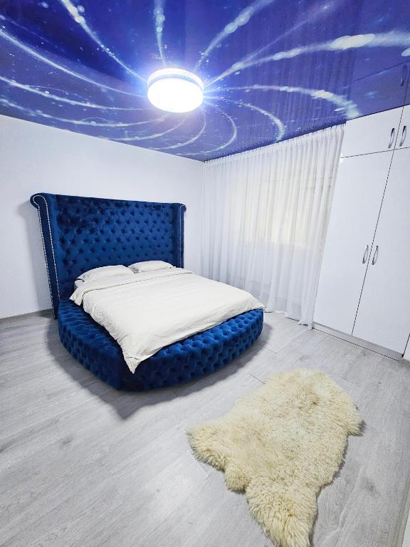 a bedroom with a bed with a blue headboard and a rug at Blue Apartament Braila in Brăila
