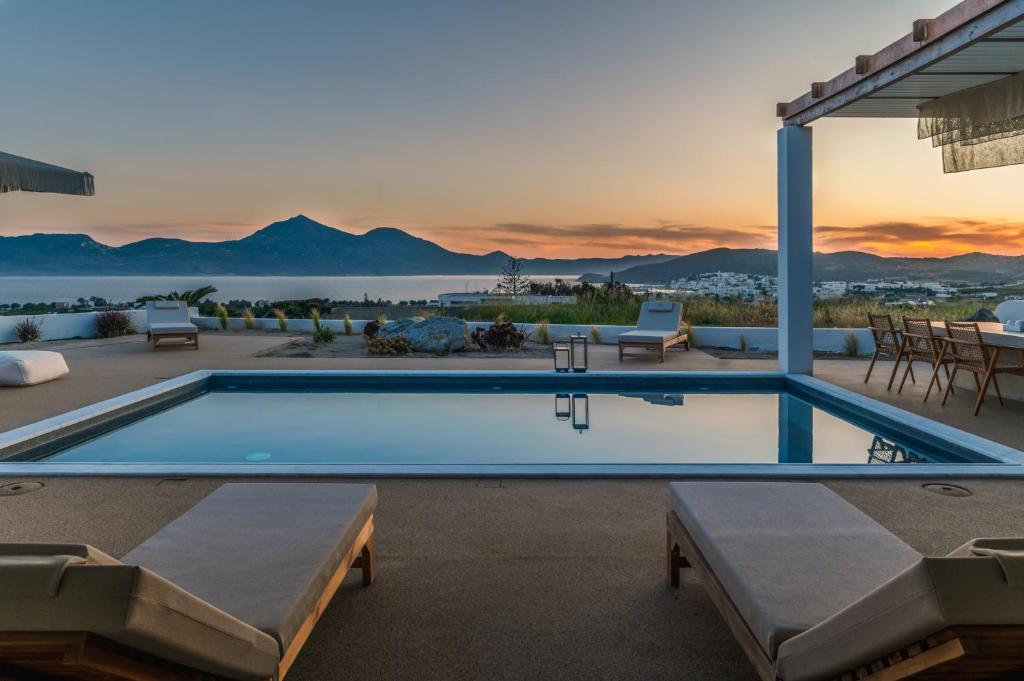 a swimming pool with a sunset in the background at Adriana Luxury Villas in Adamas