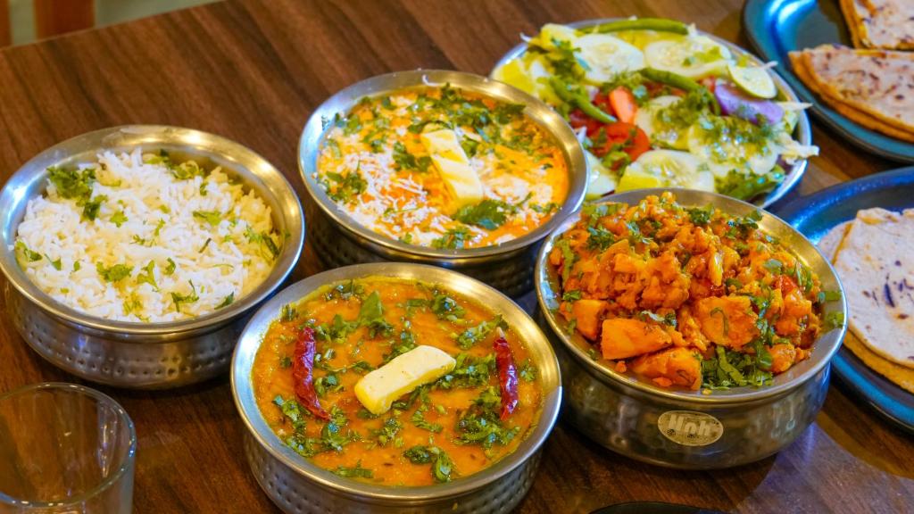 una mesa cubierta con cuencos de diferentes tipos de alimentos en Corbett Mid Forest House By Havensia Stays, en Rāmnagar