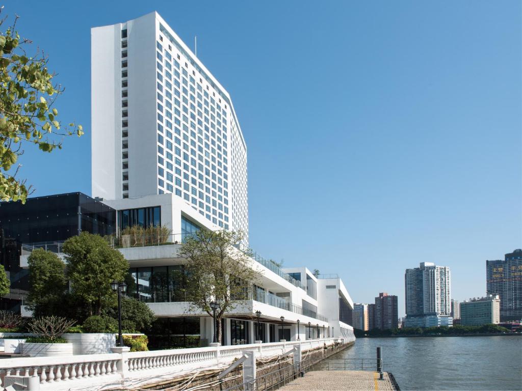 a tall white building next to a river at White Swan Hotel in Guangzhou
