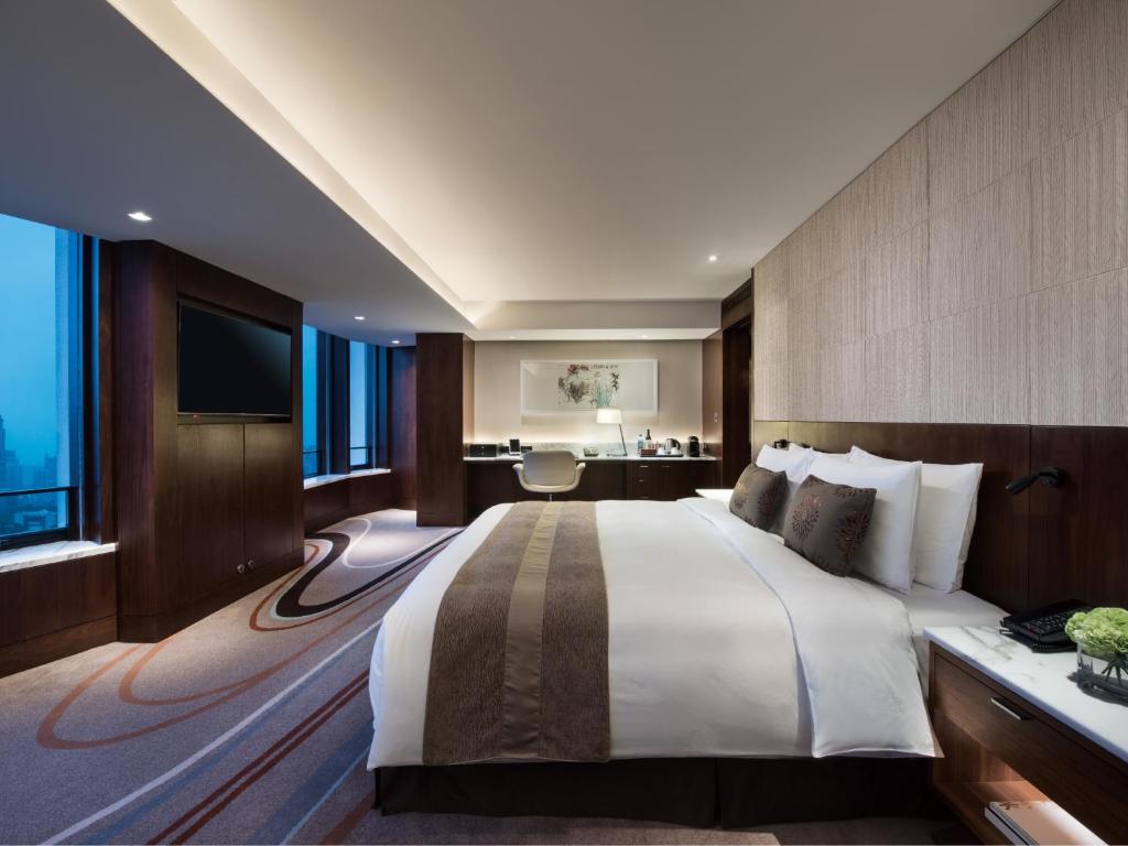 a hotel room with a large bed and a television at White Swan Hotel in Guangzhou