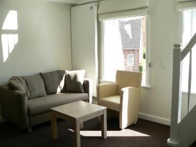a living room with a couch and a chair and a table at Apartment Im Hotel Insel Pension In Niebüll in Niebüll