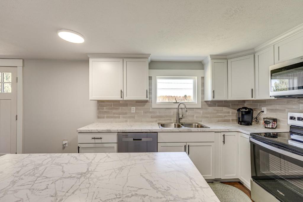 a kitchen with white cabinets and a marble counter top at Less Than 3 Mi to Double JJ Resort Home with Large Yard! in Rothbury