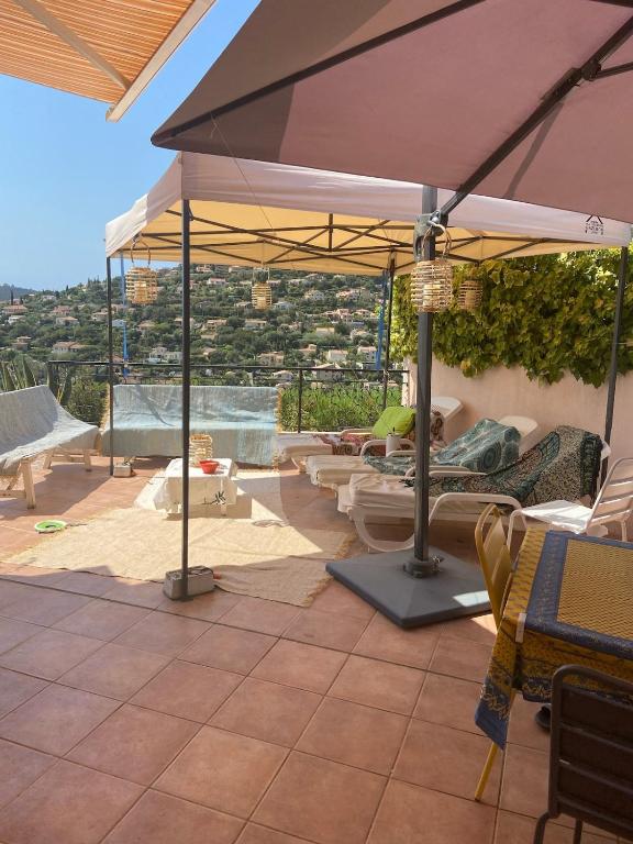 d'une terrasse avec un parasol, des chaises et des tables. dans l'établissement Maison vue mer 4 chambres - 7 min plage, à Cavalaire-sur-Mer