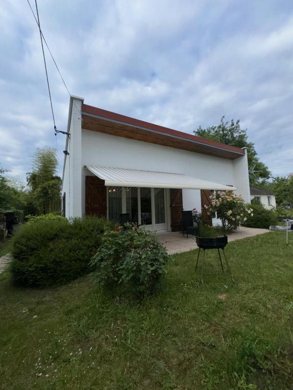 une maison blanche avec une terrasse couverte et une pelouse dans l'établissement Logement entier, à Nemours