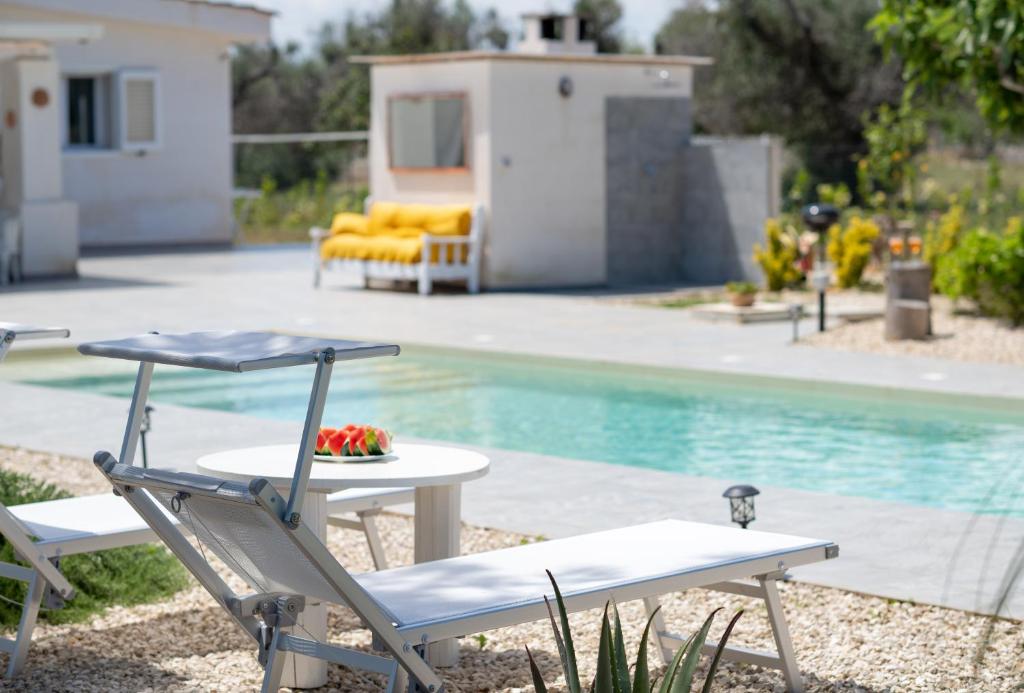 a couple of chairs and a table next to a pool at Villa Myricae by Bianco Puglia Vacanze in San Vito dei Normanni