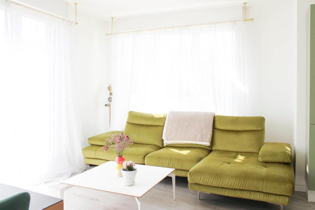 Una sala de estar con un sofá verde y una mesa. en Apartment with balcony at the gates of Paris, en Bagnolet