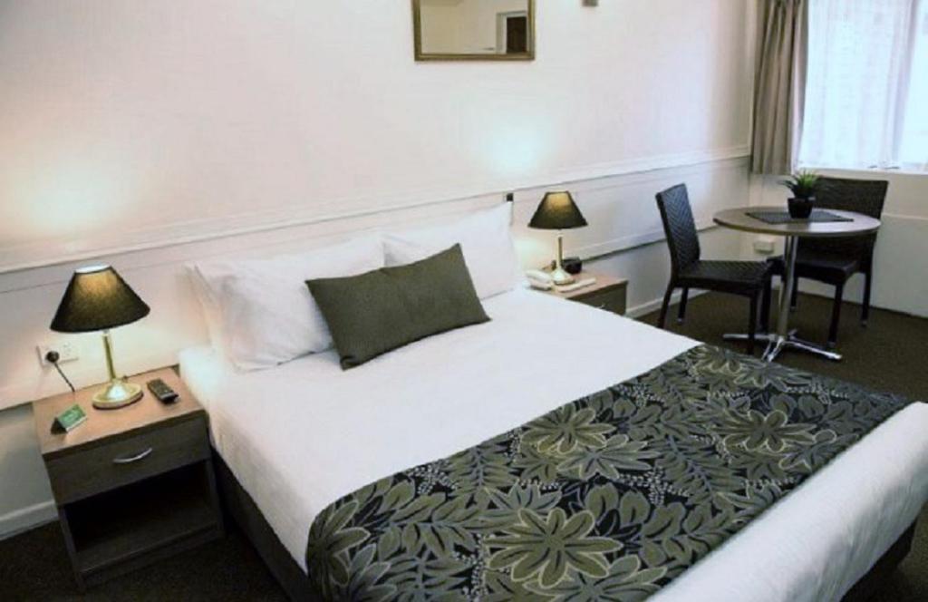 Habitación de hotel con cama, mesa y sillas en Garden City Motor Inn, en Brisbane