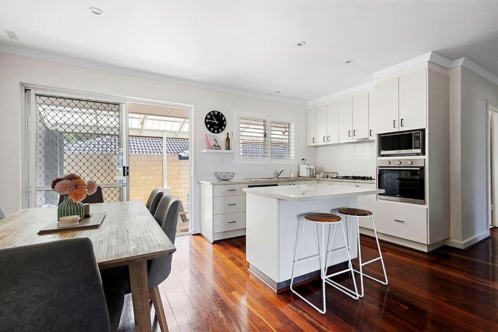 a kitchen with white cabinets and a table and chairs at Bayswater Retreat, 3 Bed house. in Perth