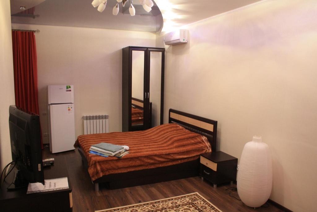 Un dormitorio con una cama y un televisor. en Apartments Galactika, en Uralsk
