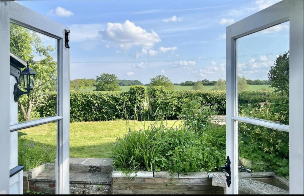 ein offenes Fenster mit Blick auf ein Feld in der Unterkunft Chelmsford Cottage Homestay Free Parking Fab Garden in Great Waltham