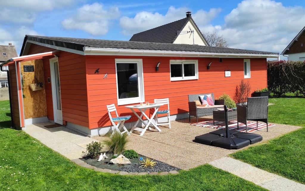 un hangar rouge avec une table et des chaises dans la cour dans l'établissement Maison tout confort, à Saint-Romain-de-Colbosc