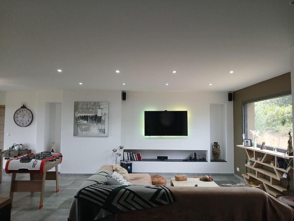 Una sala de estar con un sofá y un televisor en la pared. en Nouveau villa T4 à Sotta entre mer et montagnes, en Sotta