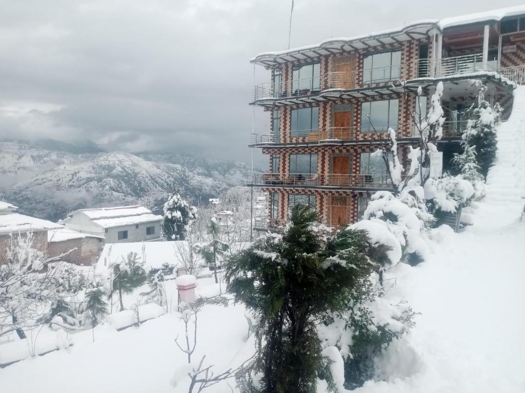 a building covered in snow in front of a mountain at BHURBAN VIEW Apartments Murree in Murree