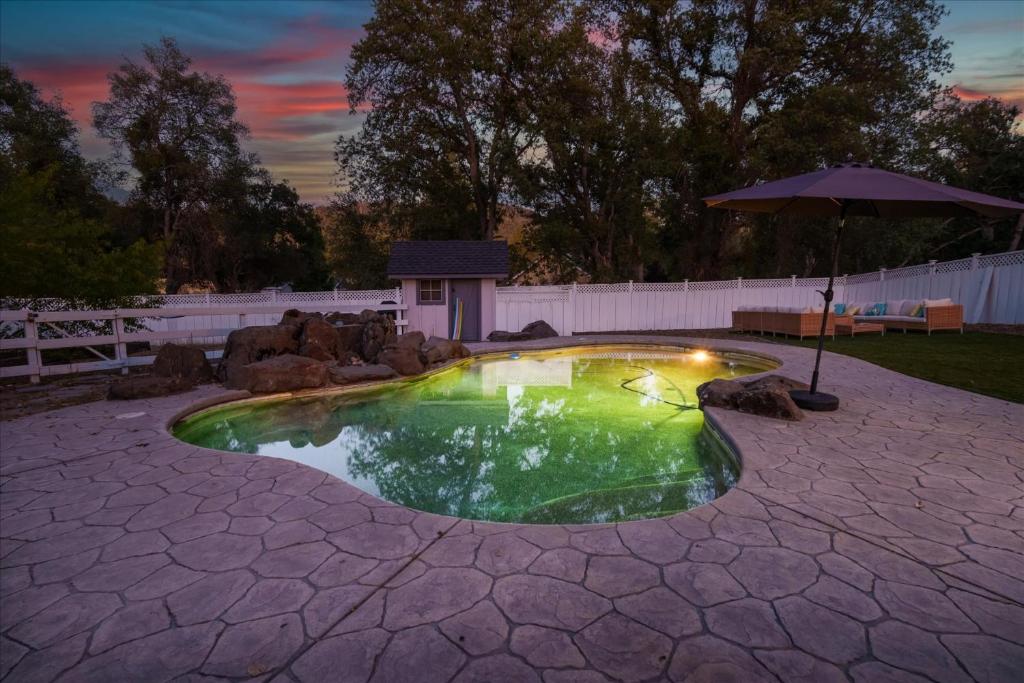 a small swimming pool with an umbrella in a backyard at Cedar Creek Lodge with POOL/hot tub/sleeps 24 in Oakhurst