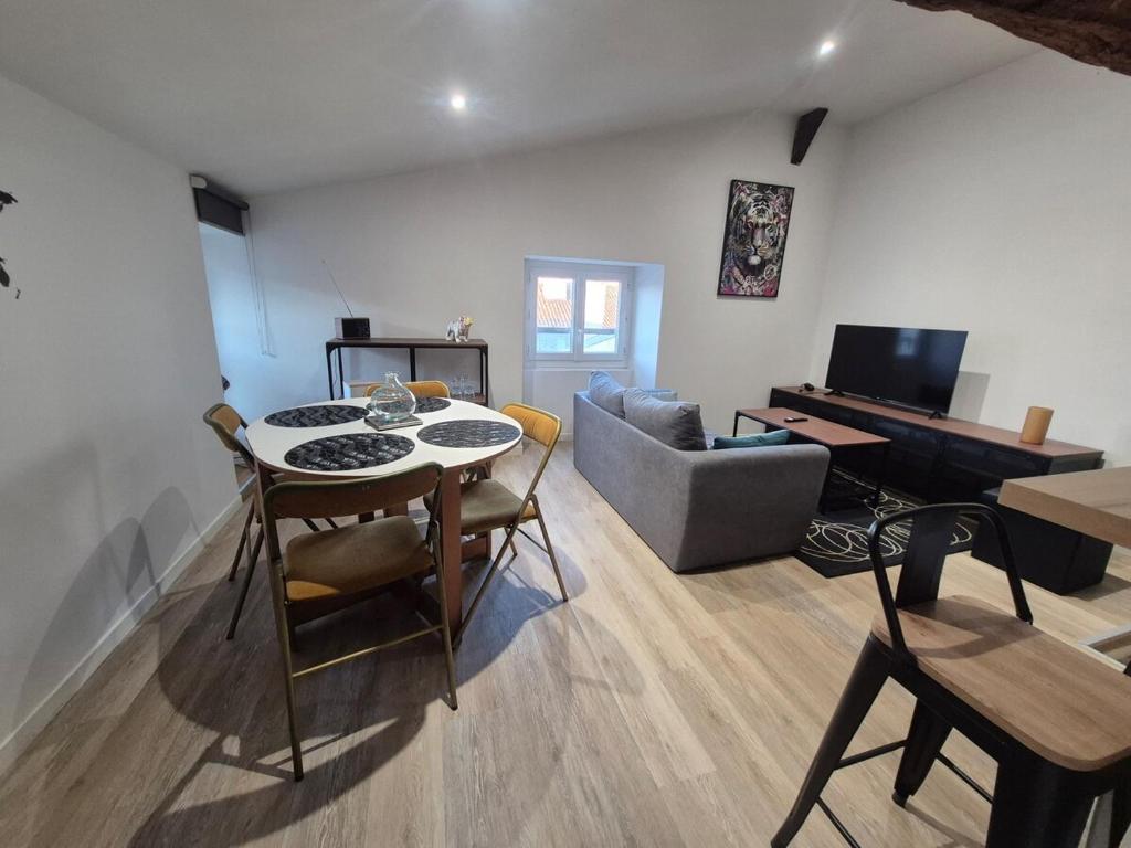 - un salon avec une table, un canapé et un piano dans l'établissement Léa, atypical and refined studio, à La Rochelle