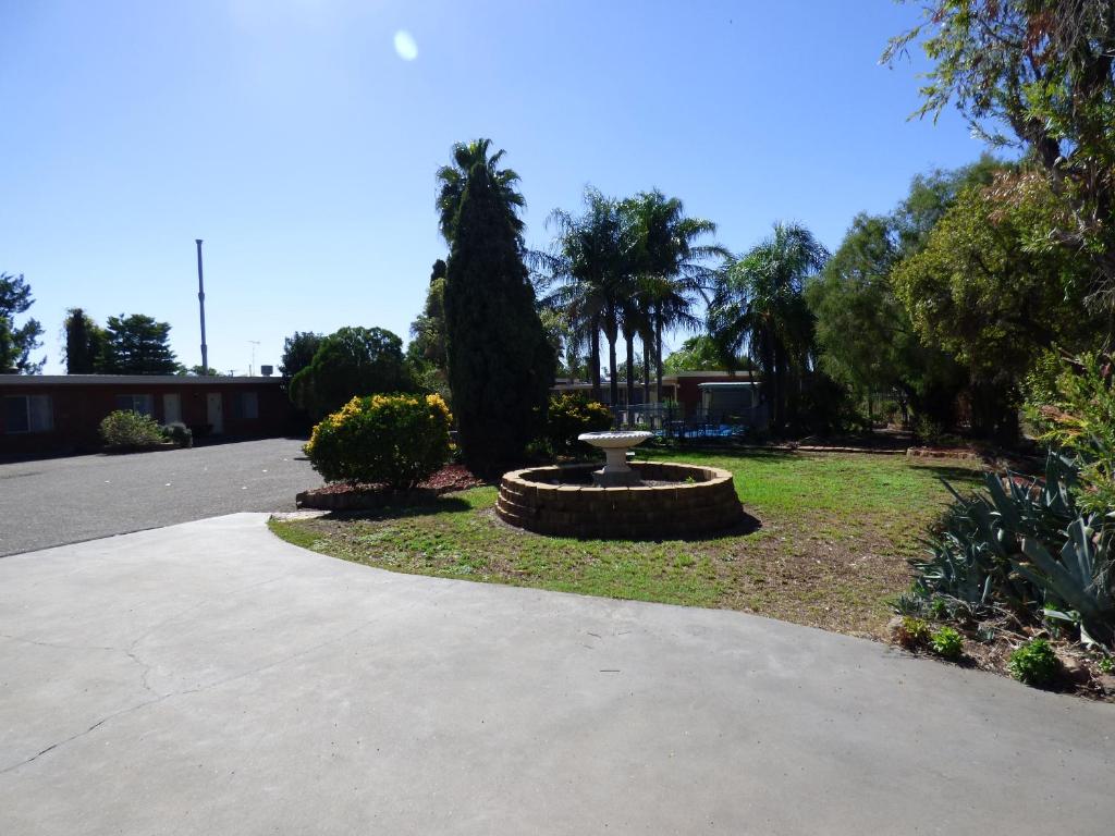 a park with a bird bath in the middle of a driveway at Red Chief Motel in Gunnedah