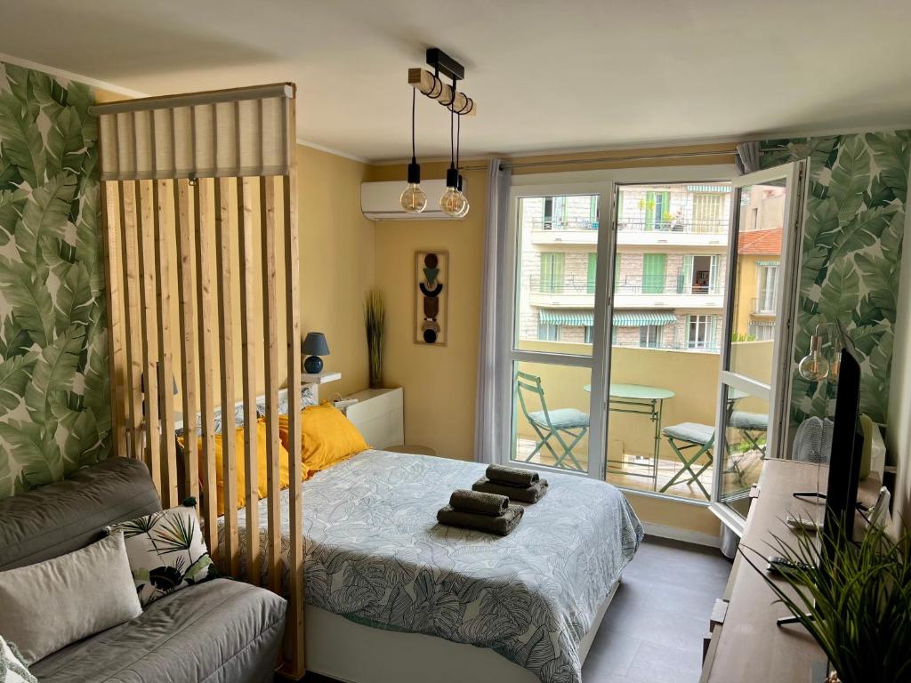 - une chambre avec un lit, un canapé et un balcon dans l'établissement Palm Leaf Studio Nice, à Nice