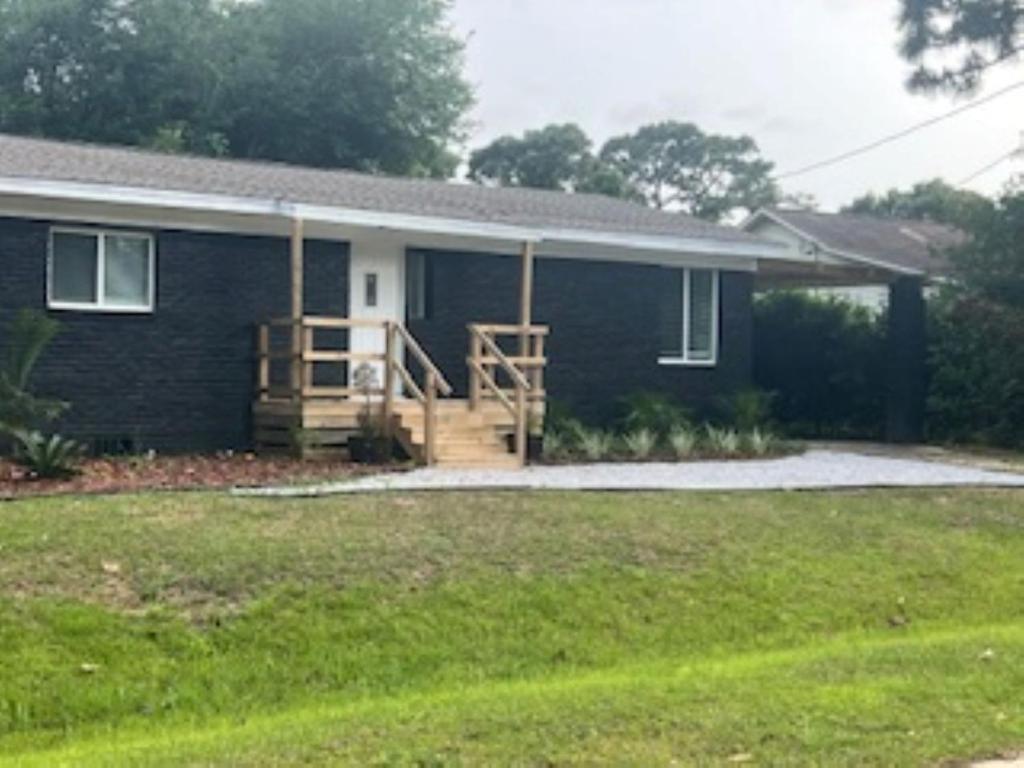 a small blue house with a porch and a yard at A Perfect Family Getaway in Pensacola