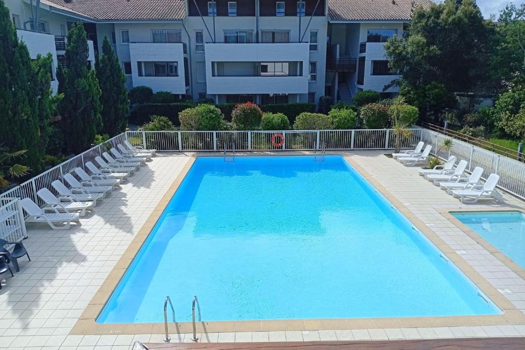 une grande piscine avec des chaises et un bâtiment dans l'établissement Superb apartment with terrace near beach, à Moliets-et-Maa