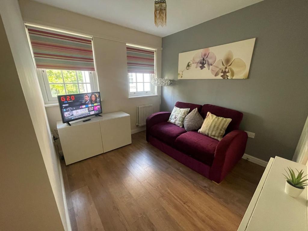 a living room with a purple couch and a tv at Gatwick 1 Bedroom Apartment in Chipstead