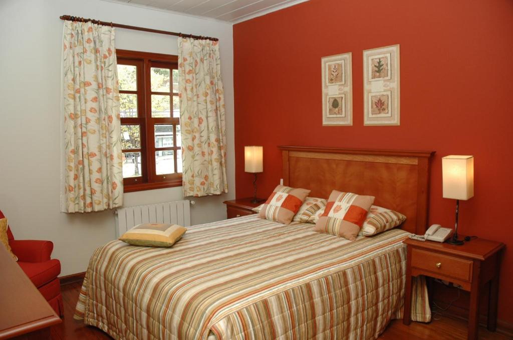 a bedroom with a large bed with red walls at Pousada Chablis in Campos do Jordão