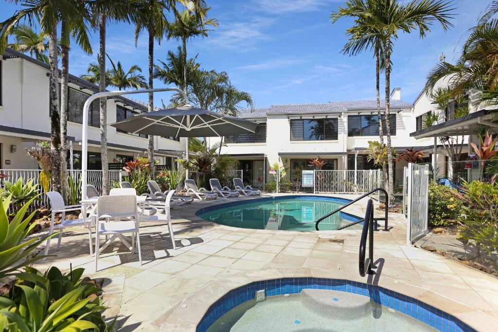 a pool with chairs and an umbrella next to a building at Noosa Place Resort in Noosaville