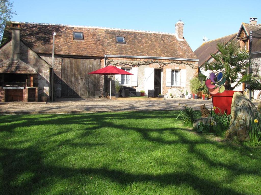 a house with a large grass yard with a red umbrella at Charmant gîte rural avec jardin, proche Amboise et Blois, idéal pour familles, randonneurs et amoureux de nature - FR-1-381-145 in Saint-Nicolas-des-Motets