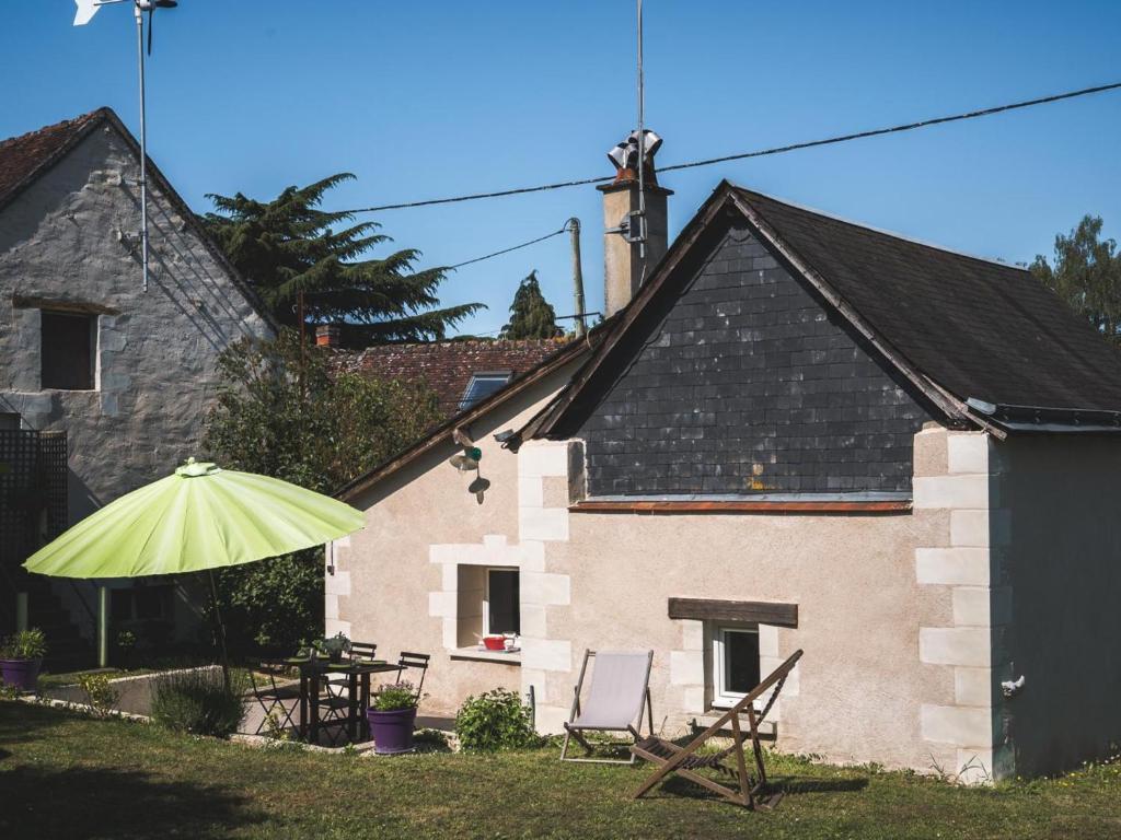 Una casa con dos sillas y una sombrilla en el patio. en Charmante maison près des Châteaux de la Loire, jardin, wifi - FR-1-381-371, en Athée-sur-Cher