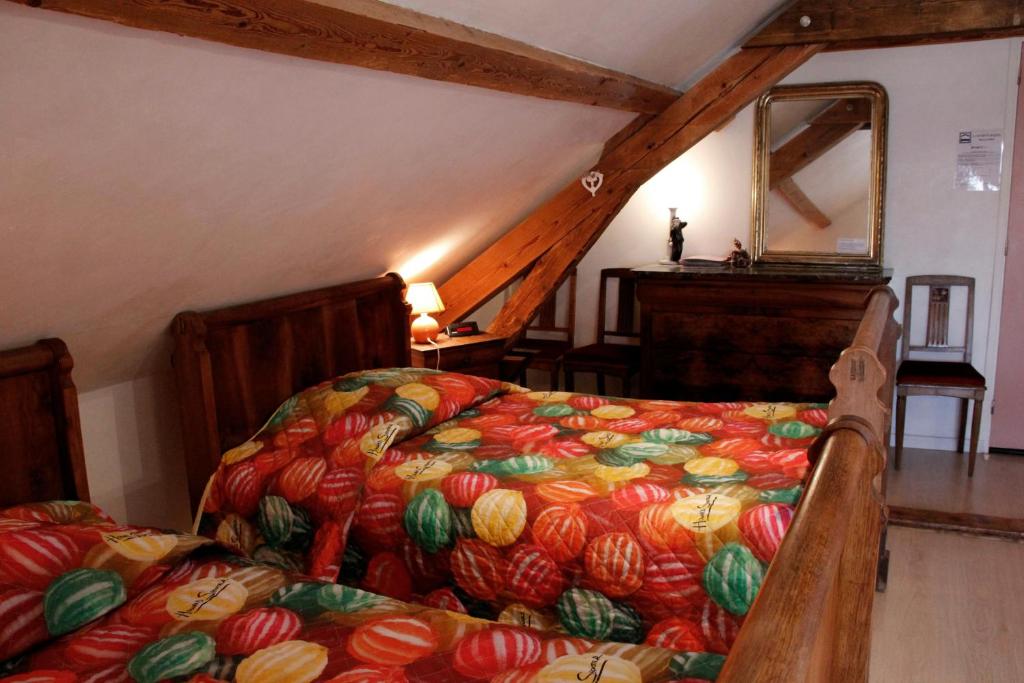 a bedroom with a bed with a colorful blanket at La Coutrotte Becquine in Heuilley-sur-Saône