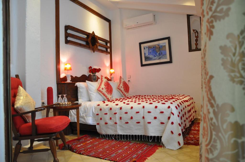 a bedroom with a bed and a red chair at Riad Cherifa in Chefchaouene