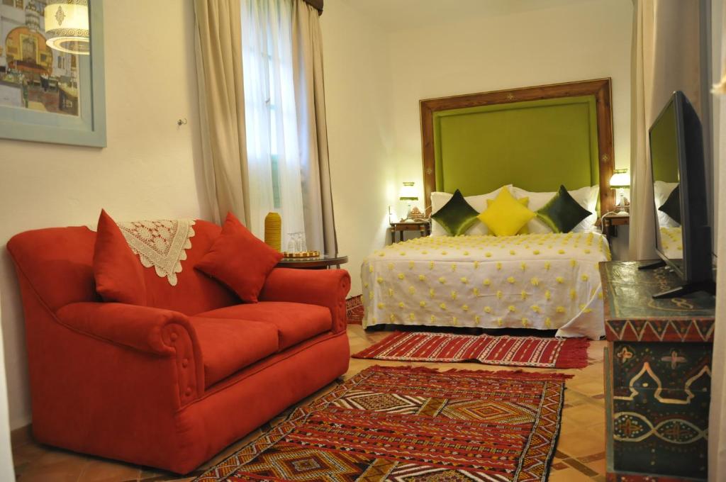 a living room with a red chair and a bed at Riad Cherifa in Chefchaouene