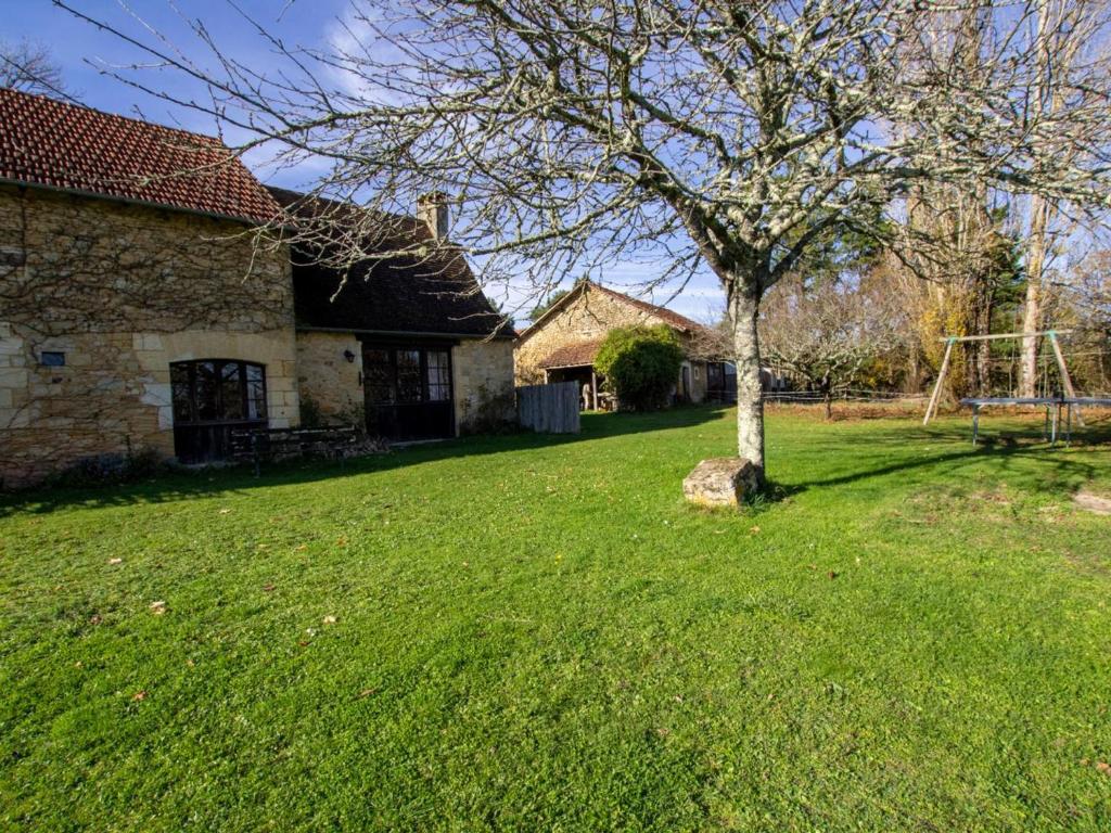 un arbre dans une cour à côté d'une maison dans l'établissement Maison avec jardin, Wifi, animaux acceptés près de Sarlat - FR-1-616-45, à Bardenac