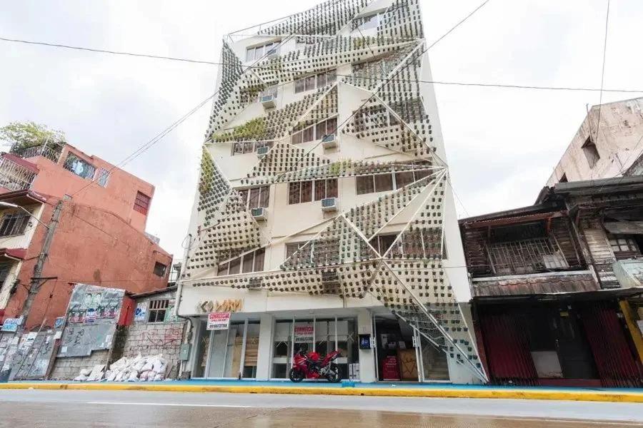 a tall white building with spiral stairs on it at Jardin Oriental Suites Ubelt Manila in Manila