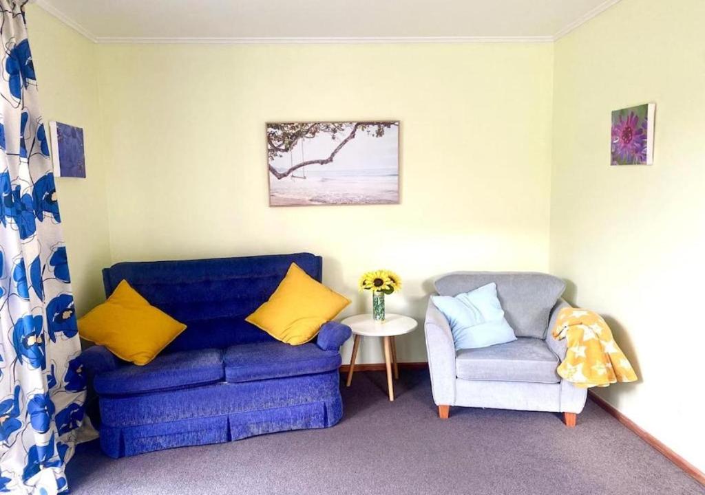 un salon avec un canapé bleu et une chaise dans l'établissement Paekākāriki Cottage near the Sea, à Paekakariki