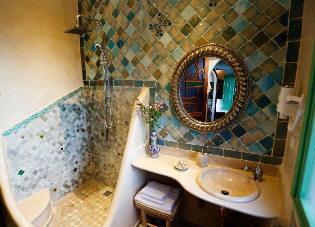 a bathroom with a sink and a mirror and a shower at Riad Cherifa in Chefchaouene