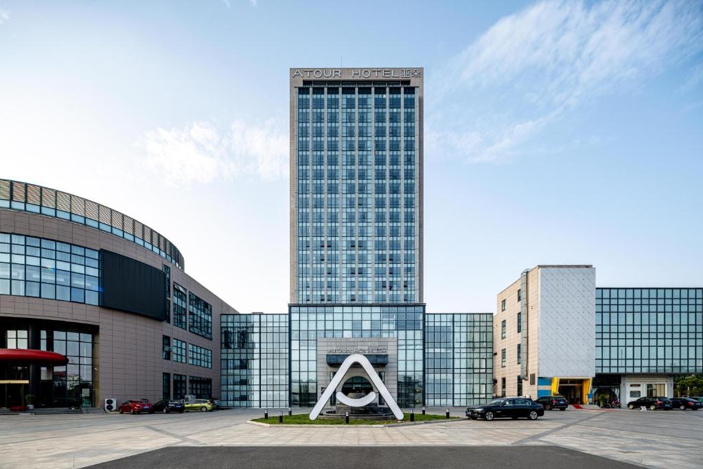 a large glass building with a sculpture in front of it at Atour Hotel Suzhou Wangting in Suzhou