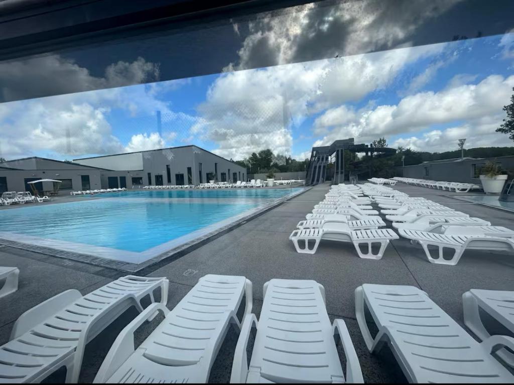 - une grande piscine bordée de chaises longues blanches dans l'établissement Mobil home tout confort, à La Celle-sous-Gouzon