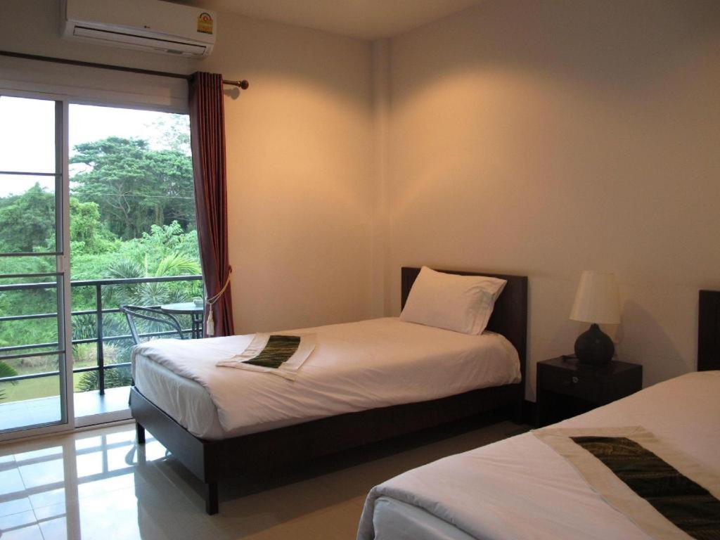Un dormitorio con dos camas y una ventana con balcón. en Sukthavorn Residence, en Ban Pa Tung (7)
